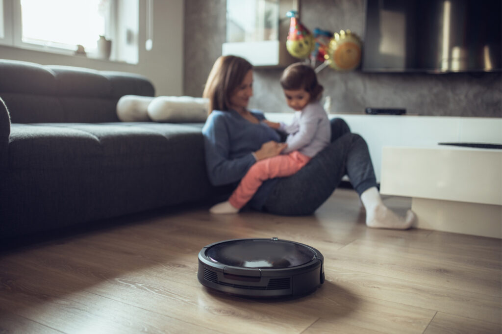 Blog hero image of electric vacuum cleaner and mother sitting on floor with child